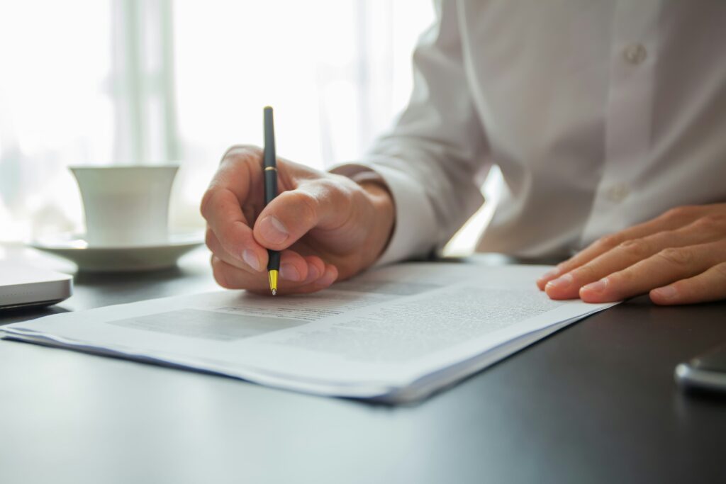 Close up of a man signing a document to comply with lending compliance.