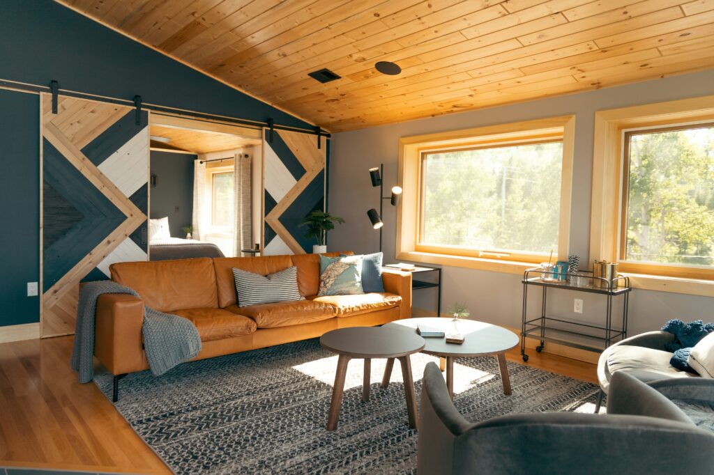 A stylish living room with a leather couch, a wooden ceiling, and sliding barn doors.