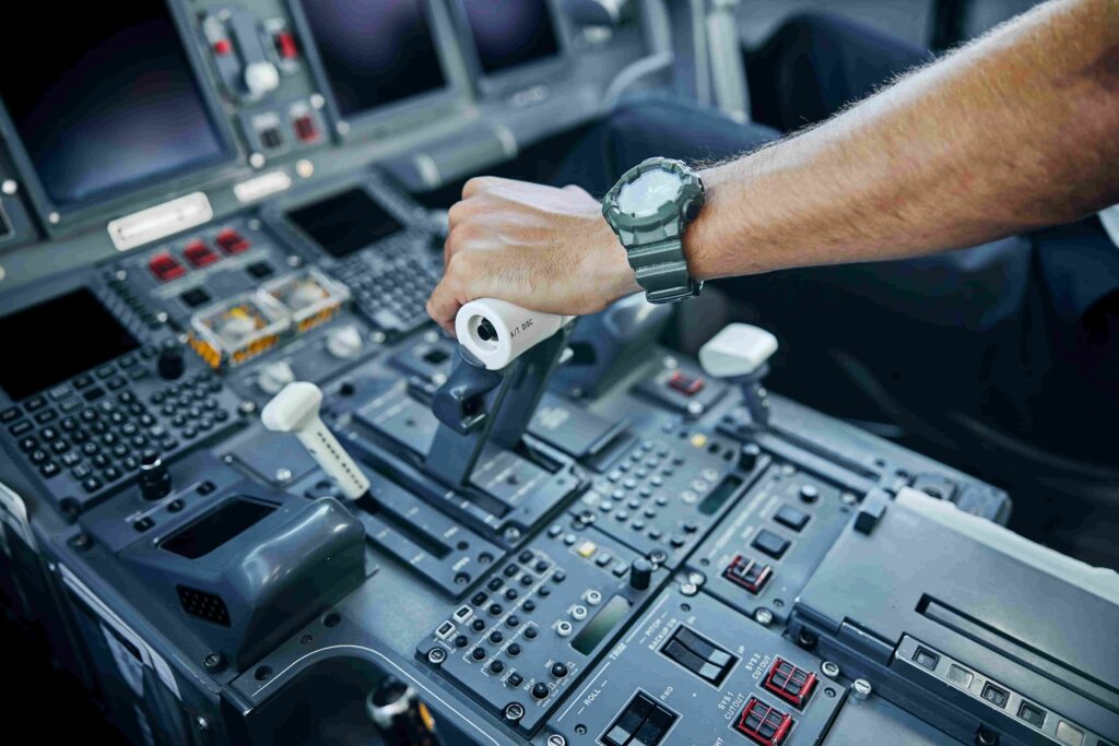 Airline pilot with a hand on the throttle lever in the cockpit of an airplane.